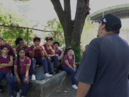 frame do documentário práticas artíticas e juventudes motra alunos reunidos em pátio escolar em atividade de poesia