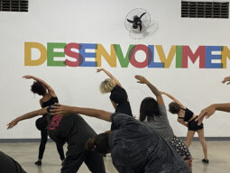 jovens participam de oficina de dança da rede de protagonismo juvenil. ao fundo, parede com a palavra desenvolvimento em letras coloridas